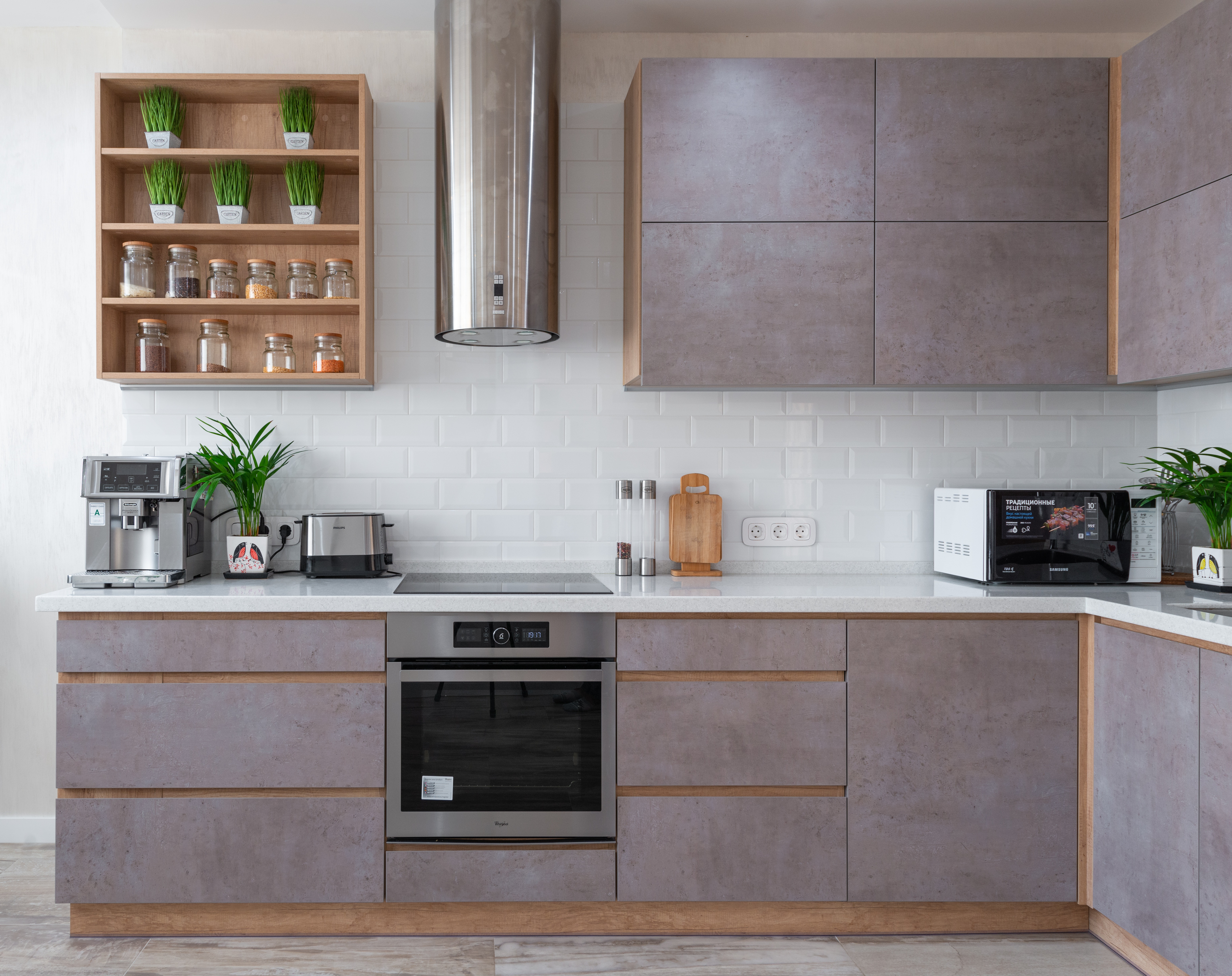 Gray toned kitchen cabinets with while backspash and a stainless steel oven. 