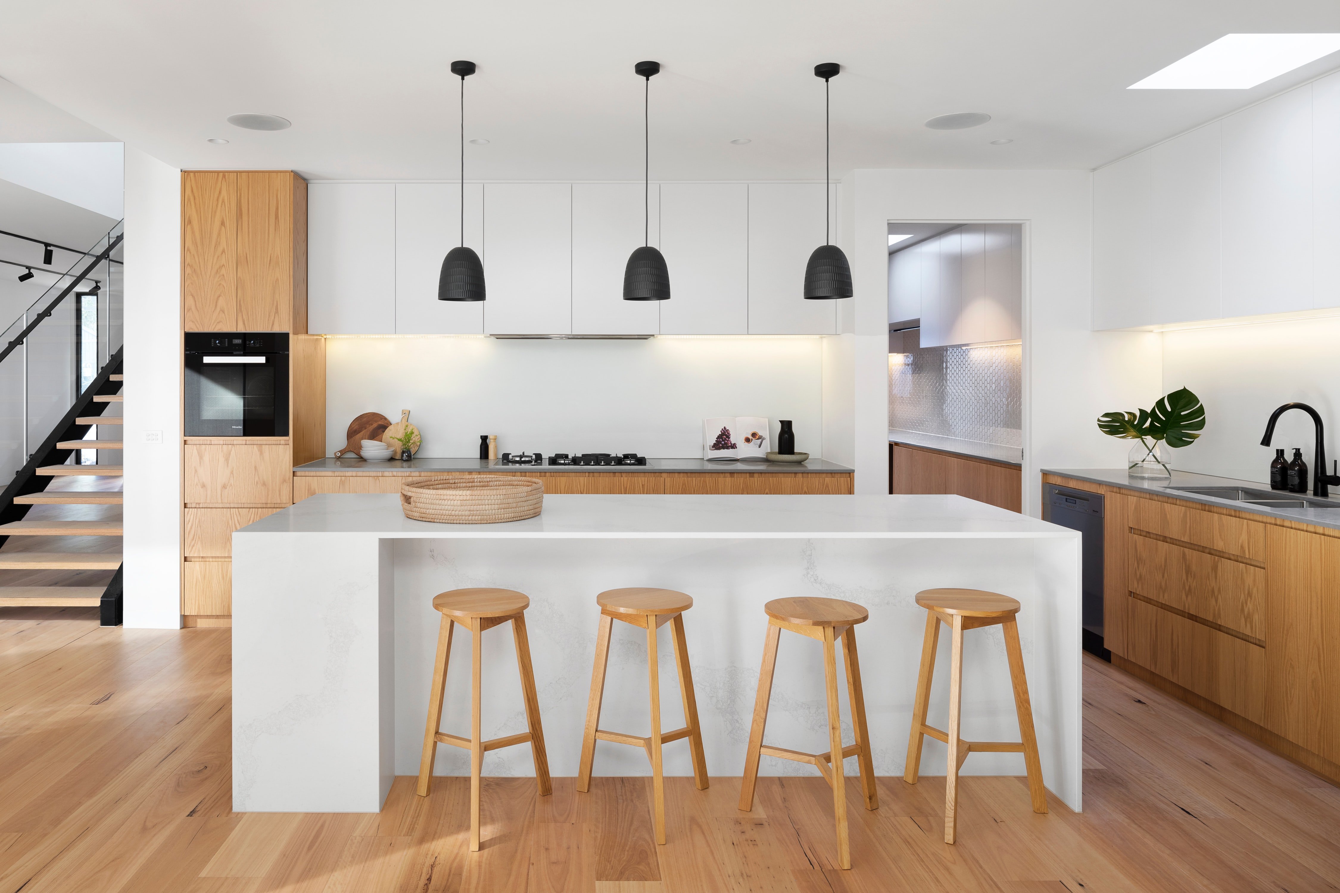 White kitchen cabinets and walls with wooden bar stools and floor.